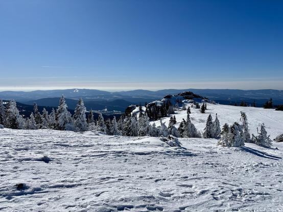 A snow-covered landscape near the summit of Großer Arber. In the background, one of the four peaks—the rock formation Bodenmaiser Riegel.