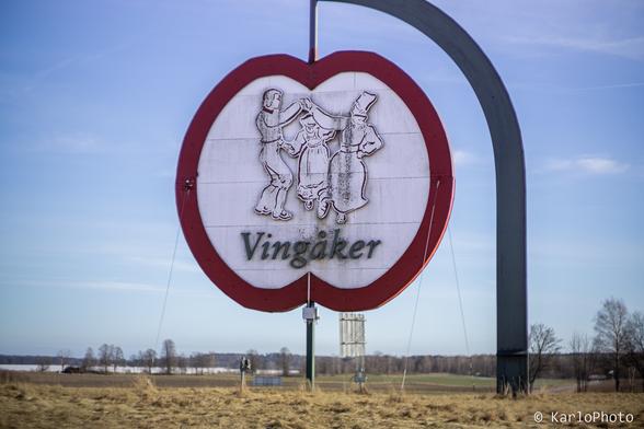 A sign shaped like an apple, with an image of two people dancing and the text "Vingåker".