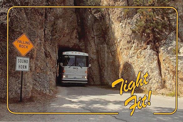 A bus barely fits in a rock tunnel as the text reads - Tight Fit!