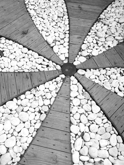 Wooden boards on white gravel making a flower pattern