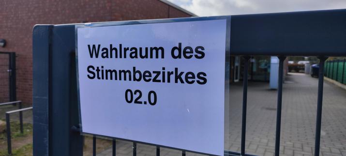 Vor dem Wahlraum, an einem Zaun der Text auf weißem Papier "Wahlraum des Stimmbezirkes 02.0"