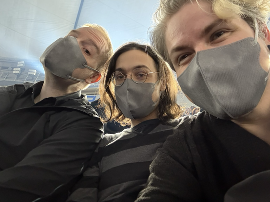 Three people smiling while wearing masks.