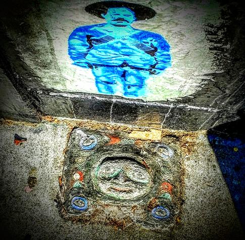 A street art plaque, roughly eroded, from a decade ago with a blue painted collaboration