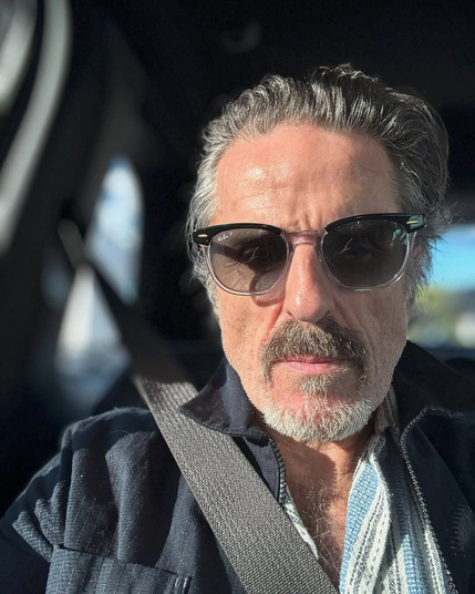 Selfie of Con sitting in a car. He is looking at the camera with a neutral expression, his eyes just visible behind a pair of sunglasses.