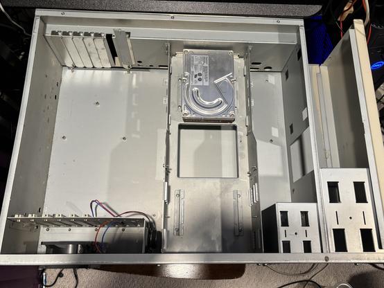 A nearly empty metal case for a Commodore Amiga 3000T, containing only the skeleton, a fan, a speaker, and a Quantum hard disk.
