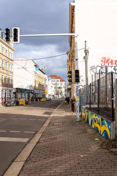 Blick entlang einer Straße. Das Licht lässt es so wirken, als käme der Ausleger einer Ampel aus einer Häuserwand.