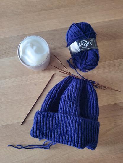 DEU Eine fast fertig gestrickte, blaue Mütze. Es fehlt nur noch die Spitze. 

ENG A blue knitted hat, nearly finished. A Set of double pointed needles holds the stitches on top of the hat.