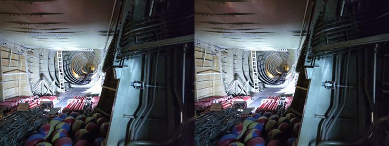 Stereoscopic, parallel view. Interior of an enormous seaplane, looking back toward the tail. It resembles the scene in Pinocchio when Geppetto has been swallowed by Monstro the whale. For some reason, there are a bunch of beach balls in the lower right of the image. Something about buoyancy, I think, but I didn't read the signs very carefully.