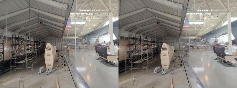 Stereoscopic, parallel view. A diorama of the construction of the Spruce Goose seaplane. We are inside a recreation of the hanger in which it was built. Similar to the previous view, but with the wing under construction more prominent. We can see that this is a diorama, because on the right side of the image, we can see out into the museum proper.