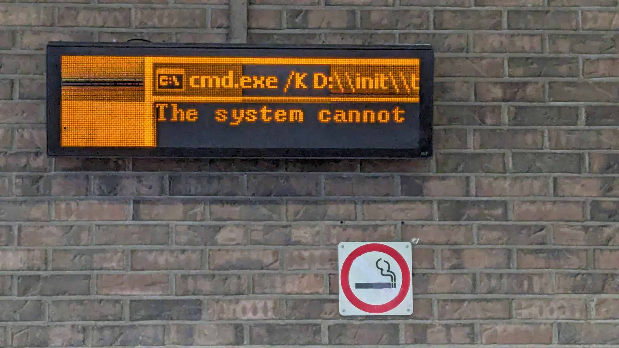 An electric sign that is clearly broken which reads: "C:\ cmd.exe /K D:\init\t The system cannot"