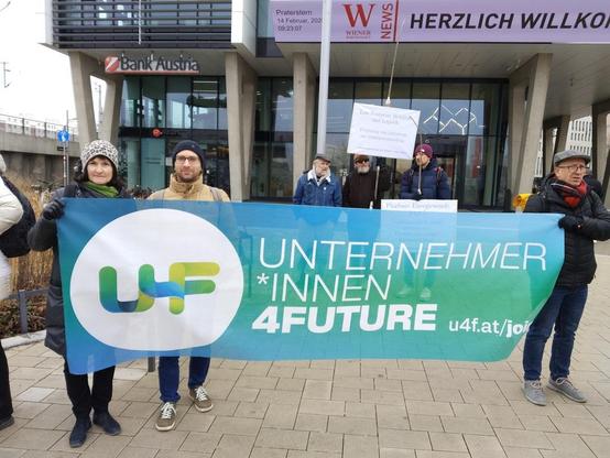 Gemeinsam mit zwei Unternehmer:innen halte ich ein U4F Plakat auf der Demo vor der WKO Zentrale