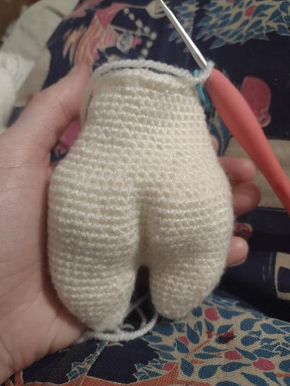 The back of a palm sized, half finished amigurumi. It has two dump legs, a pronounced bum and tapered waist.