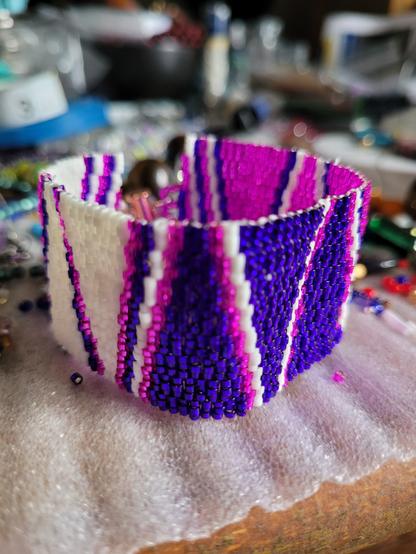 Zigzag/chevron three drop peyote bracelet of white, silver-lined purple, and silver-lined hot pink Delica beads. A two-hole clasp attaches the ends together
