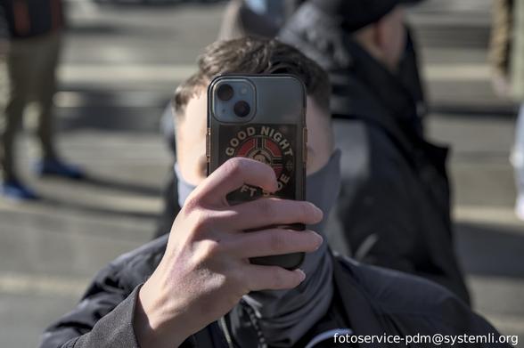 eine vermummte person hält ein handy richtung kamera, auf der rückseite: ein sticker mit rechskriegsfahne, in der mitte ein ss-totenkopf, welcher ein dahinterliegendes hakenkreuz abdeckt. umschrieben mit "good night left side"