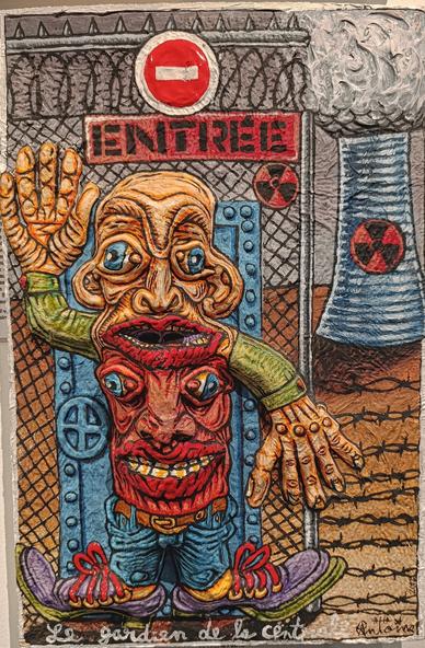Photo d'un tableau avec relief représentant un personnage grotesque et inquiétant, nommé « Le gardien de la centrale ». Son visage est déformé, monstrueux, avec pour torse un deuxième visage tout aussi horrible. Son corps semble fusionné avec différents membres, créant une impression d’hybride monstrueux. L’arrière-plan montre une grille, un panneau « ENTRÉE » interdit et des tours de refroidissement ornées de symboles nucléaires. Les couleurs sont vives et contrastées, ainsi que le relief marqué du matériau.