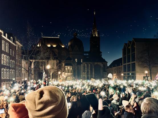 Blick auf den Katschhof in Richtung des aachener Doms im Einbruch der Dunkelheit. Der Platz ist hell erleuchtet durch unzählige Lichtpunkte der Handytaschenlampen von den Demonstrierenden.