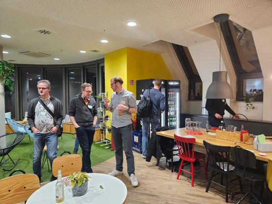 A lot of fun and intensive discussions at the Scrumtisch Cologne. People standing together and talking (maybe about agile topics).