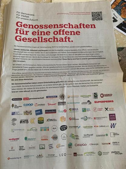 Das Bild zeigt einen Zeitungsartikel aus der Zeitung taz mit dem Titel "Genossenschaften für eine offene Gesellschaft". Darunter sind die Logos von vielen Genossenschaften, die diese Botschaft unterschrieben haben.