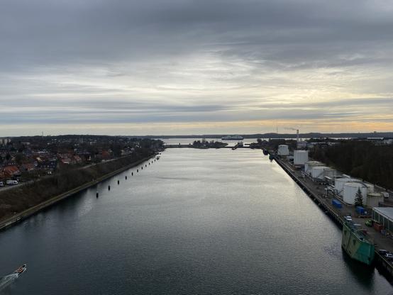 Blick auf die Nord-Ostsee-Kanal-Schleuse Holtenau von der Prinz-Heinrich-Brücke aus. Ein kleines Motorboot fährt im Kanal, in der Kieler Förde jenseits der Schleuse fährt die Color Line in Richtung Norwegenkai.