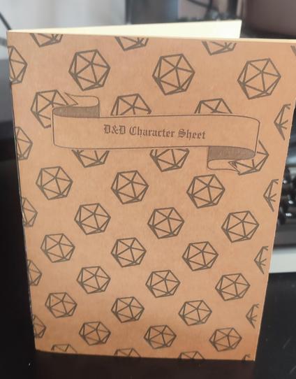 A softcover booklet, text on the front-cover is: D&D Character Sheet, and the has a pattern of D20s