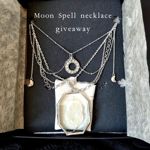 A necklace in its elegant packaging. The necklace is an outstanding piece made of silver multichains, with tiny moon crescents on the sides, a moon phases pendant and a glass medallion showcasing a real lunaria annua disc that looks like the moon. It's displayed on black cardboard with holes to to keep the necklace safe for transportation. The text above reads “Moon Spell necklace giveaway”.
•
Un collier dans son emballage élégant. Le collier est une pièce exceptionnelle composée de chaînes multiples en argent, avec de petits croissants de lune sur les côtés, un pendentif représentant les phases de la lune et un médaillon en verre mettant en valeur un véritable disque de lunaria annua qui ressemble à la lune. Le tout est présenté sur un carton noir percé de trous pour protéger le collier lors de son transport. Le texte au-dessus indique « Moon Spell necklace giveaway » (concours collier Moon Spell - sortilège de la Lune).