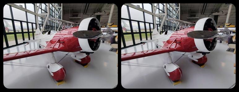 Inside an air museum, a beautiful, bulbous, red and white 1930s racing monoplane with a chrome propeller. Stereoscopic, color view for parallel viewing.