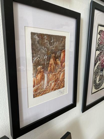 John Blanch Art Print framed. The scene is mountains, and cliffs with a lightening streaked dark skyline looking over a waterfall. Reds, browns, and oranges are the primary colours.