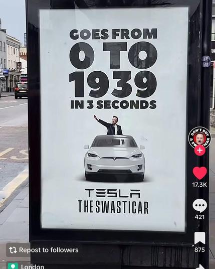 An ad on a bus stop depicting a white Tesla car on a white background. Behind the car stands Elon Musk doing his Nazi salute from Trump's 2025 inauguration.

Above the car and Elon is written "Goes from 0 to 1939 in 3 seconds".

Below them: "Tesla the Swasticar"