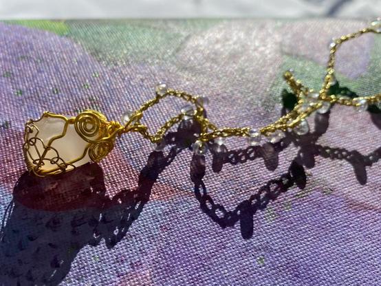 Luminous translucent  white agate wrapped into a one inch tall pendant with gold colored wire. It hangs from a custom crochet 22 inch necklace made with gold cord.