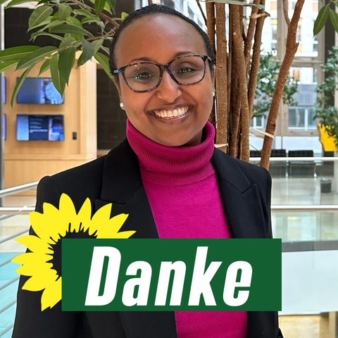 Eine Frau mit einem großen Lächeln. Auf dem Foto steht mit großen Lettern das Wort „Danke“. Eine Sonnenblume ist auf der linken Seite der Schrift zu sehen.