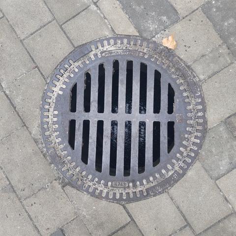 Metal manhole cover with many small, elongated openings.