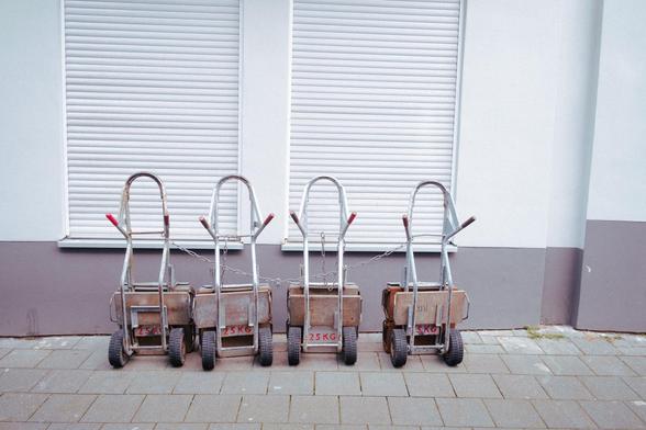 4 aufgereite Sackkarren vor einem Haus mit heruntergelassenen Rolläden