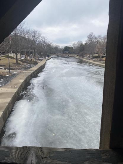 View from a bridge of a frozen river with patches of water visible again