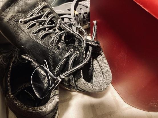a pair of glasses in an old shoe next to a red bucket