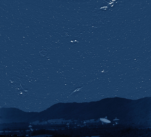 The lower half of the image shows a radio astronomy observatory off in the distance, nestled in front of mountains. Prominently standing out from the dark image is a large, white radio dish antenna, with several smaller antennas also located nearby. The sky above the mountains is freckled with point sources of light. In addition, there are translucent, globular structures and bright, irregularly shaped structures. The light points are the supermassive black holes and the other structures are from our own Milky Way Galaxy.