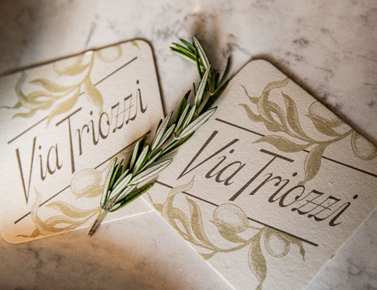 Photo of two coasters with a script logo for “Via Triozzi”.