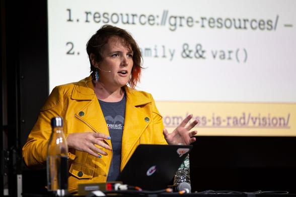 Portrait de l’autrice, portant un blouson de cuir jaune, au cours d’une intervention à une conférence sur les CSS.