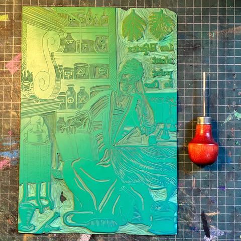My half carved green vinyl Lino block on a cutting mat with small u gauge with wood handle. The block is carved in reverse with 17th century lady in a dress leaning on a table with head resting on one hand as she reads a book. She is surrounded by tools of her trade like vessels of various shapes, scales and has shelves of jars with alchemical symbols on them. There is text, carved in reverse with elongated s’s with a quotation, ‘Les Esprits n’ont point de sexe’ (or minds have no sexe… that is, one’s sex is irrelevant to the ability to think and learn).