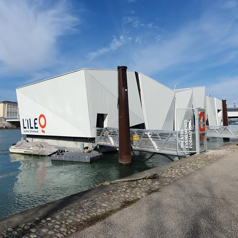 Photo du théâtre de l'île Ô. C'est un bâtiment flottant blanc composé de sortes de gros cubes blancs. La photo est prise depuis le quai juste à côté du théâtre.