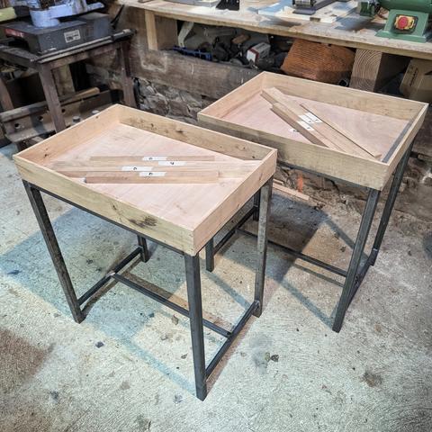 Dans l'atelier, deux tables dont il manque les couvercles vitrés 
Les plateaux sont des boites de 10 cm d'épaisseur. Les pieds sont métalliques. On voit les montant des couvercles démontés dans chaque boite.