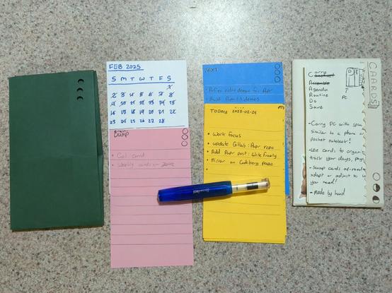 From left to right:
Green "Papr Companion."
White Calendar Card
Pink Brain Dump card:
- Cal card
- Weekly cards <--
Blue Next card:
- Refine video demos for Papr
- Build Papr (-) demos
Yellow Today Card 2025-02-25:
- Work focus
- Update Gitlab: Papr repo
- Add Papr post: WriteFreely
- Mirror on Codeberg

White Paper Companion Prototype:
CAARDS acronym brainstorming.
PC + CAARDS sketch.
- Carry PC with you similar to a phone or a pocket notebook.
- Use cards to organize and track your days, physically.
- Swap cards as-needed, and adapt or adjust to whatever you need.
- Made by hand

Photo by, SelfDugGrave