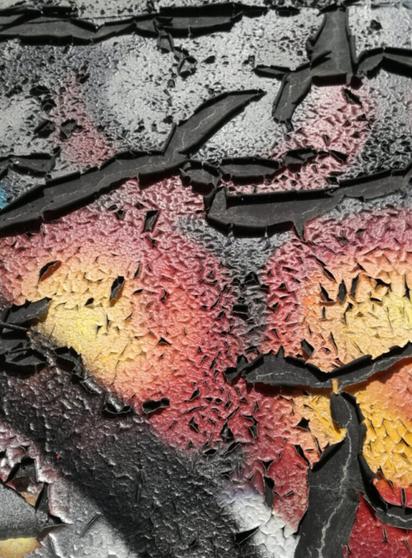 Abblätternde Farbe auf einer Metalloberfläche in Rot, Gelb, Grau und Silber.