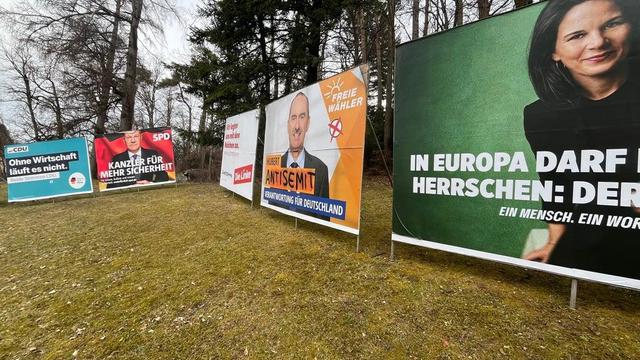 Das Bild zeigt eine Reihe von Wahlplakaten verschiedener deutscher Parteien, die auf einer Wiese aufgestellt sind. Von links nach rechts sind Plakate der CDU ("Ohne Wirtschaft läuft es nicht"), der SPD ("Kanzler für mehr Sicherheit"), der Linken, der Freien Wähler (mit dem Aufdruck "Antisemit") und der Grünen ("In Europa darf nicht herrschen: Der Hass"). Die Plakate stehen vor Bäumen und einem bewölkten Himmel.

Bereitgestellt von @altbot, generiert mit Gemini