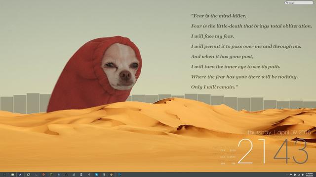 A screensaver with the Litany Against Fear on the upper right hand side over blue grey sky. Across the bottom is rolling sand dunes. The sandworm coming up from behind the the sand dune is what looks like an unhappy squinting chihuahuas face sticking out of the arm hole of someones red sweatshirt.
