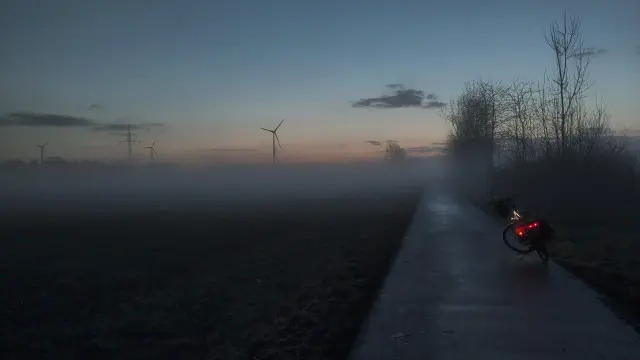 Rad auf Wirtschaftsweg , blauer Himmel bevor die Sonne aufgeht. Nebelschwaden liegen über Feldern und und Weg