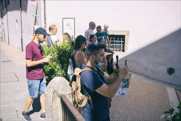 Foto di turisti con in mano i cellulari intenti a fotografare la cattedrale di Spoleto, dall'alto della scalinata di fronte al Duomo.