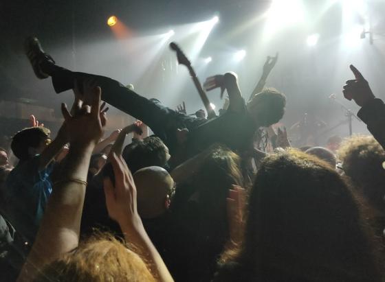 Le guitariste se jette dans le public guitare en main pour un slam des familles. Le public le fait passer de main en main dans une chaude ambiance comme on l'imagine 😉