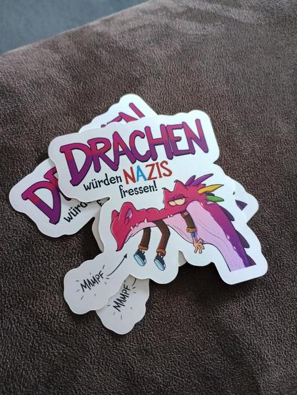 Sticker mit einem rosa drachen der einen Nazi frisst. Cartoon Stil
