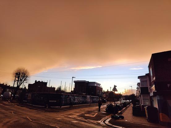 A street scene with an incredibly orange/brown cloud with some very blue sky on the horizon. The contrast is incredible.