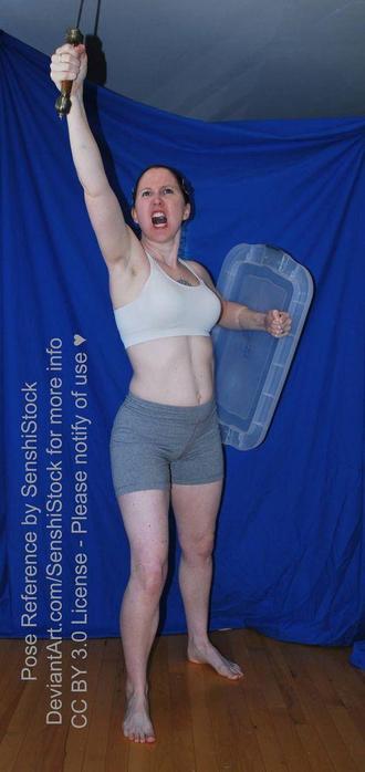 A white woman standing, facing 3/4 towards the camera, arm extended upwards, holding a sword by the hilt and yelling, her other hand holding a shield behind her.